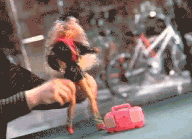 a pixelated image of a person playing with a barbie doll and a pink suitcase