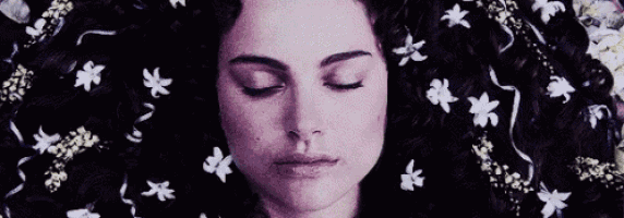 a woman is laying in a bathtub surrounded by flowers and ribbons .