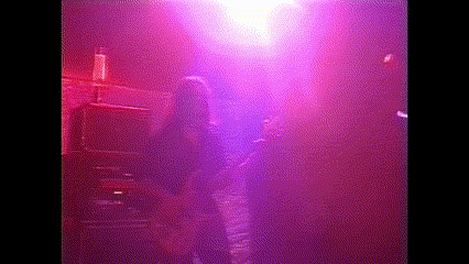 a woman is standing in a dark room with purple lights behind her