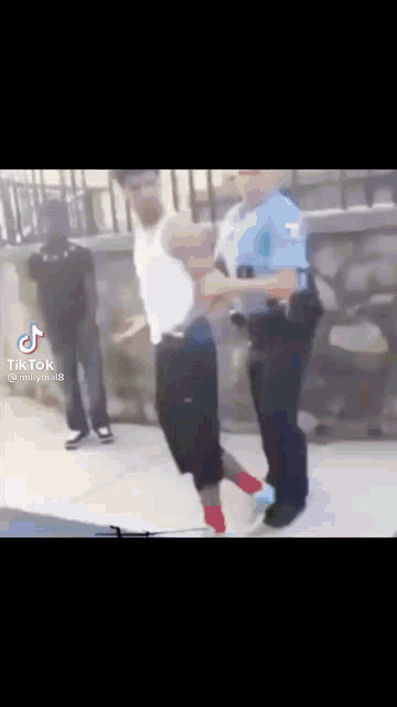 a police officer is holding a man in his arms while another man looks on .