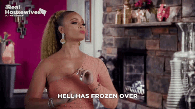a woman in a pink dress is standing in front of a fireplace and says " hell has frozen over "