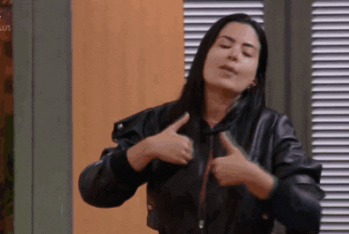 a woman in a leather jacket is giving a thumbs up sign