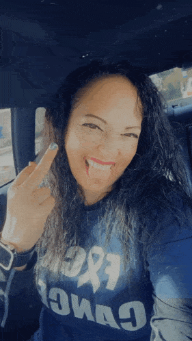 a woman in a blue shirt that says iowa on it is giving the middle finger