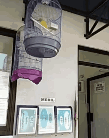 a cage with a bird in it hangs from the ceiling above a sign that says mobil