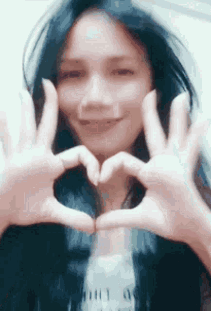 a woman is making a heart shape with her hands .