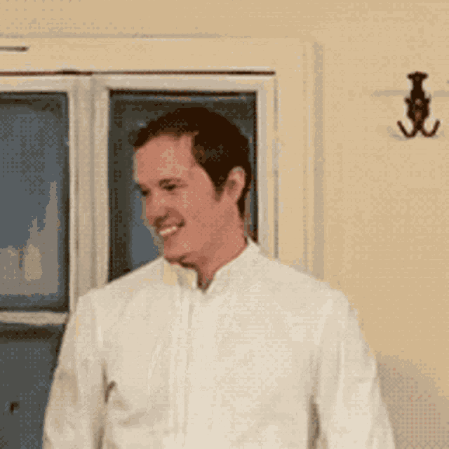 a man in a white shirt is standing in front of a window