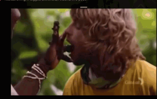 a man in a yellow shirt is being eaten by a monkey