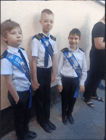 three boys wearing sashes with the year 2012 on them stand next to each other