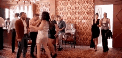 a group of people are dancing in a room with a patterned wall .