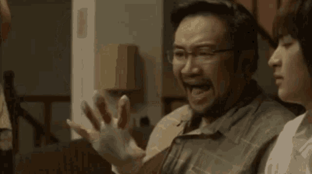 a man and two women are standing next to each other in a room . the man has blood on his hands .