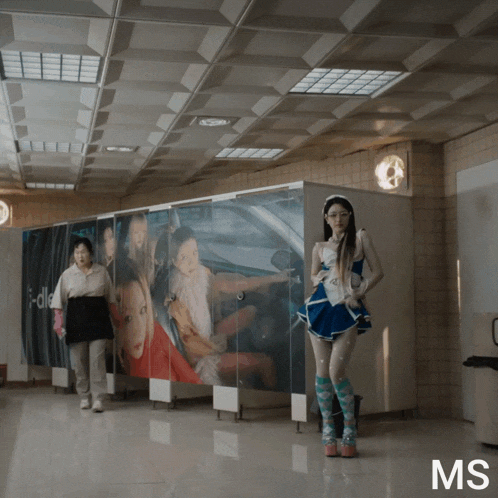 a woman in a blue dress is standing in front of a wall with pictures of women on it