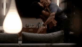 a man and a woman kissing on a couch in a living room