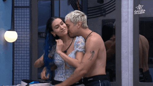 a man and woman are kissing in front of a sign that says estrella