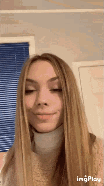 a girl with long blonde hair wearing a white turtleneck sweater
