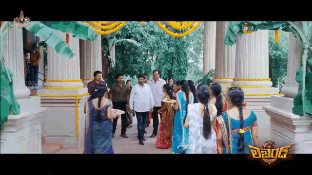 a group of people are standing in front of a building with a sign that says ' telugu ' on it .