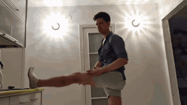 a man stretches his leg in a kitchen with a light that says ' c ' on it