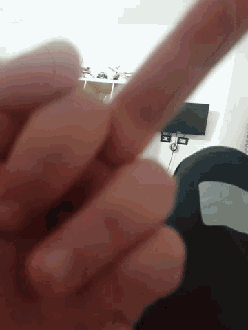 a close up of a person 's finger with a tv behind it