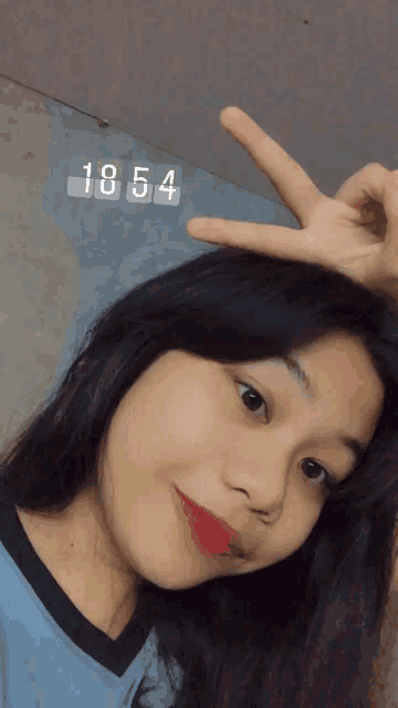a girl giving a peace sign with the number 1854 above her