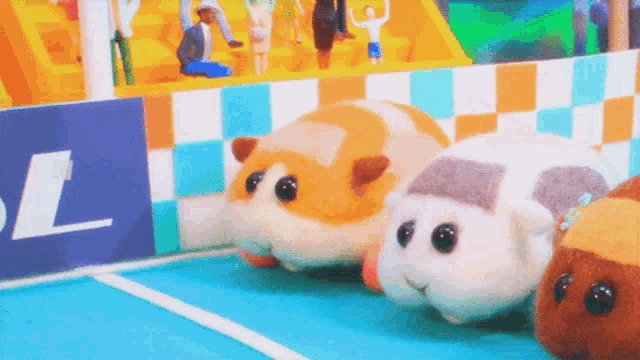 three stuffed animals are racing on a track with the letter l visible in the background