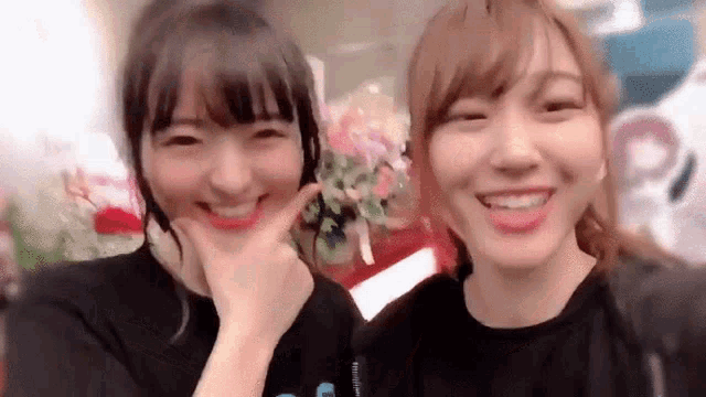 two young women are standing next to each other smiling and making funny faces .