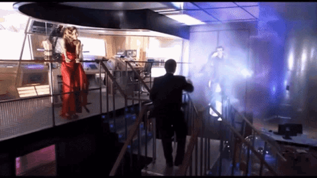 a man in a suit and a woman in a red dress are walking down a set of stairs