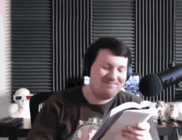 a man wearing headphones is reading a book and smiling