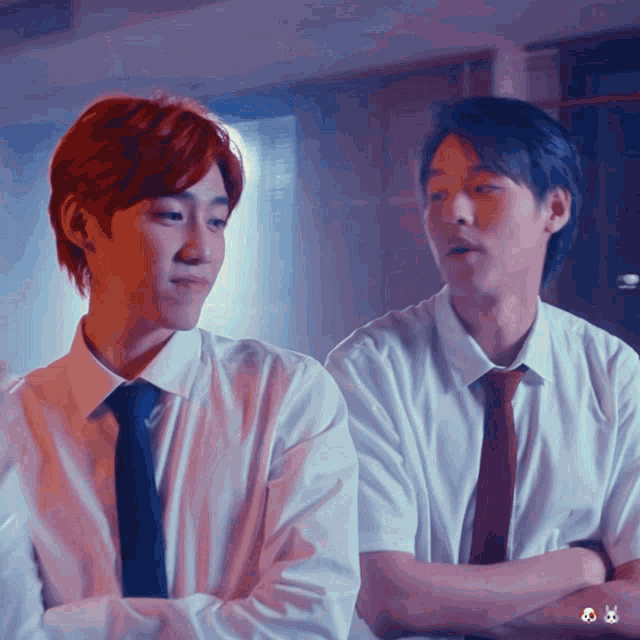 two men standing next to each other with their arms crossed
