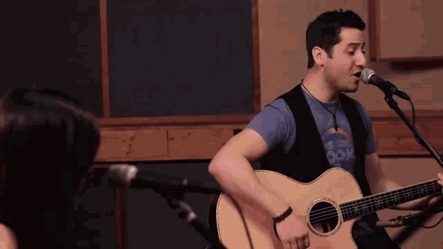 a man is singing into a microphone while playing an acoustic guitar