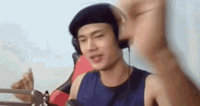 a man wearing headphones and a beret is sitting in front of a microphone and making a funny face .