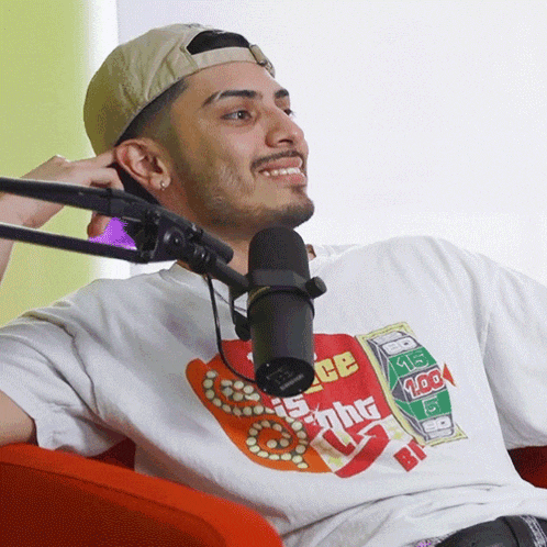 a man wearing a t-shirt that says " sight " is sitting in front of a microphone