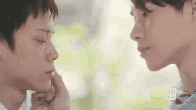 two young men are touching each other 's faces and looking at each other .