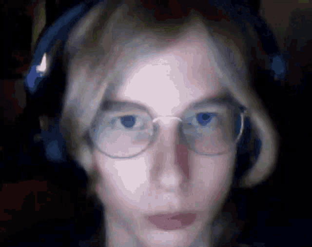 a person wearing glasses and headphones looks at the camera