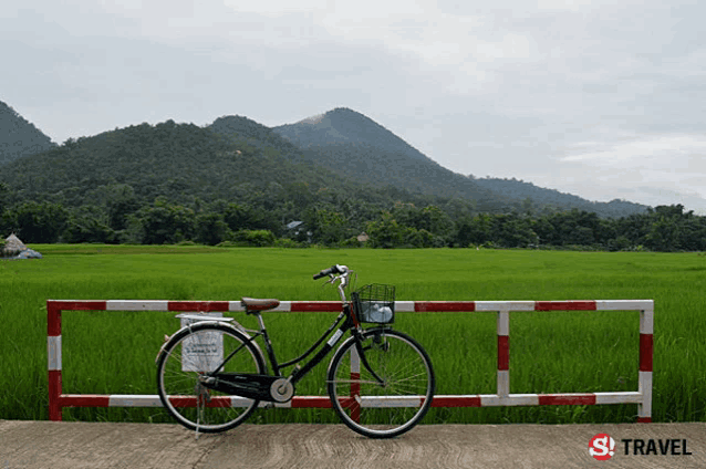 a bicycle is parked behind a red and white barrier in front of a field