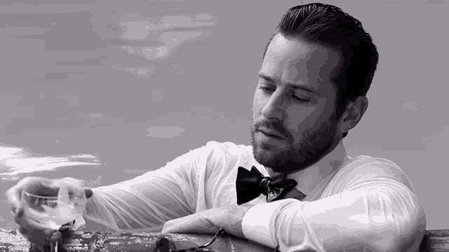 a man in a bow tie is holding a glass