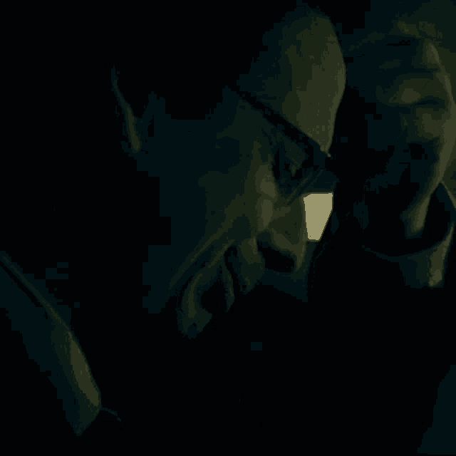 a man in a suit and tie is talking on a cell phone in the dark