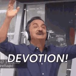 a man wearing headphones is waving his hands in the air and saying devotion !