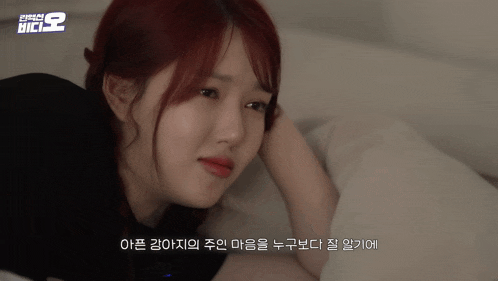a woman with red hair is laying on a bed with korean writing on the bottom