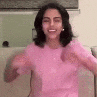 a woman in a pink shirt is sitting on a couch with her arms outstretched .