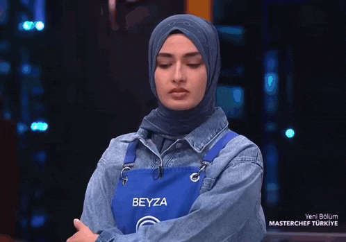 a woman wearing a blue apron with beyza on it