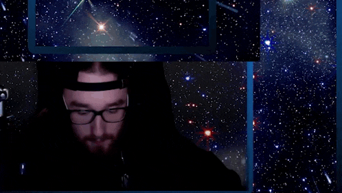 a man with a beard wearing glasses and headphones is smiling in a dark room .