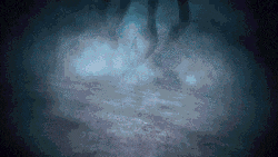 a person is walking through a dark room with a spotlight on the floor .