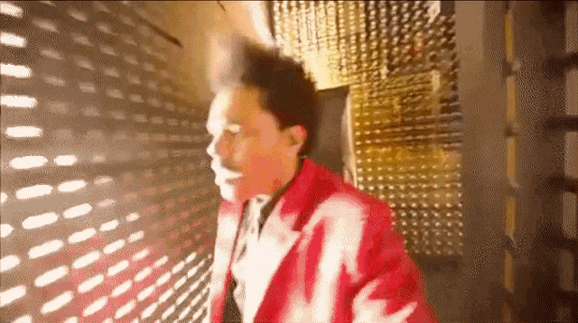 a man in a red jacket and tie is walking through a doorway .