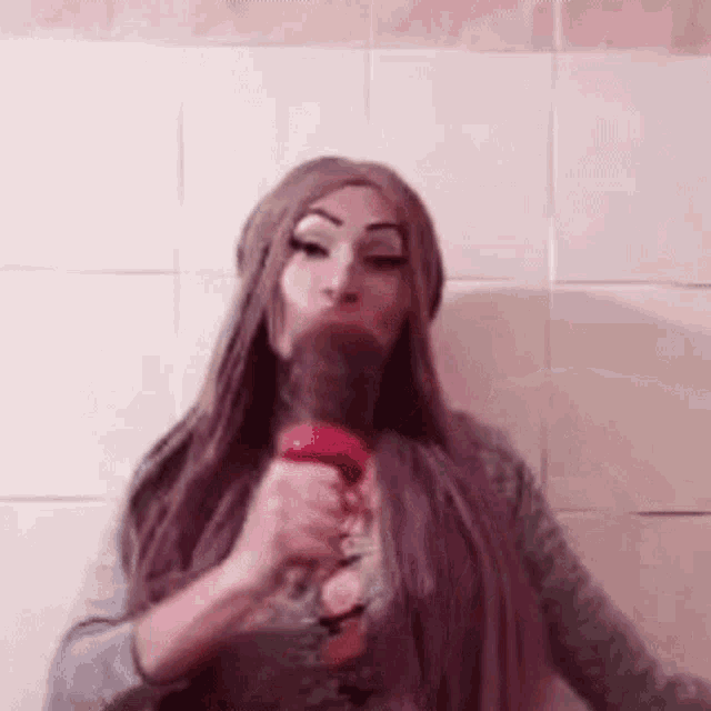 a woman in a purple wig is blow drying her hair with a hair dryer .