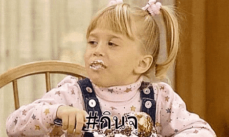 a little girl is sitting in a chair eating a cake with a fork .