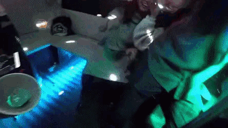 a man and a woman are dancing in a dark room with green and blue lights on the floor