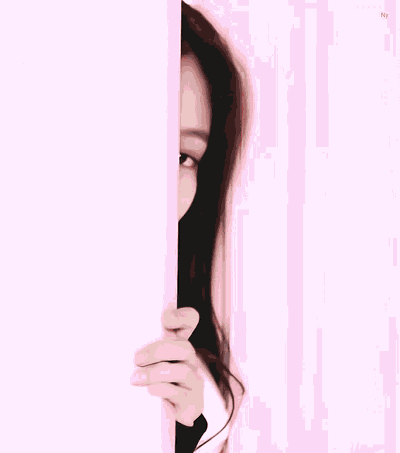 a woman peeking out from behind a wall with her hand on her face