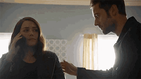 a man and a woman are standing next to each other and the woman is talking on the phone