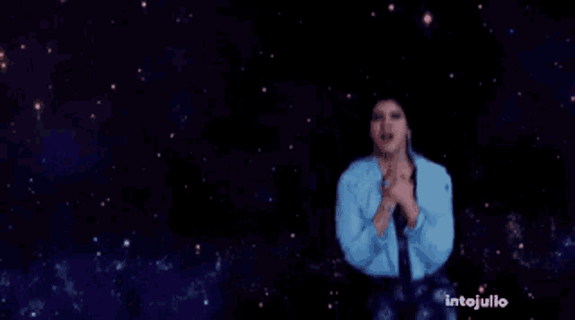 a woman in a blue jacket is standing in front of a galaxy .