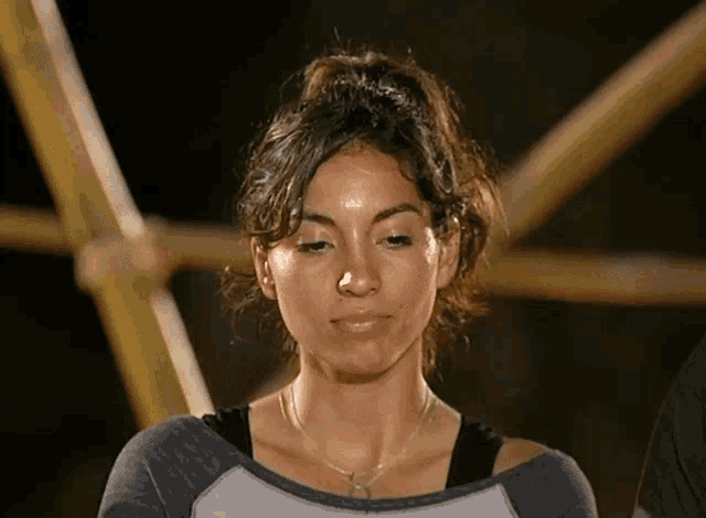 a woman with a ponytail and sweat on her face looks down