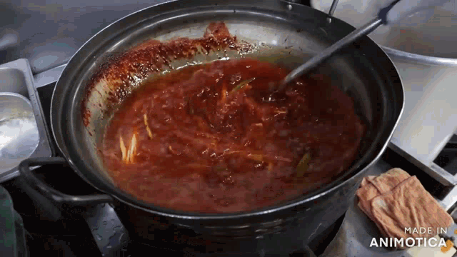 a pot of tomato sauce is being stirred with a spoon and the words made in animatica are visible